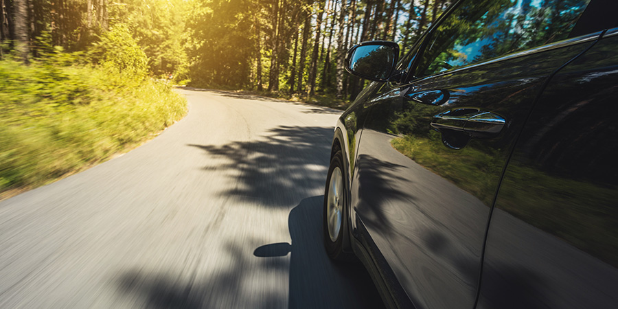 Featured Image of the driving assessment blog. A car driving along a forest road.
