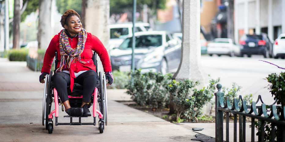 Smiling woman in wheelchair on the sidewalk of a city
