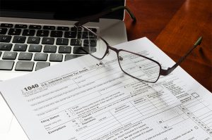 1040 income tax return form with MacBook and glasses