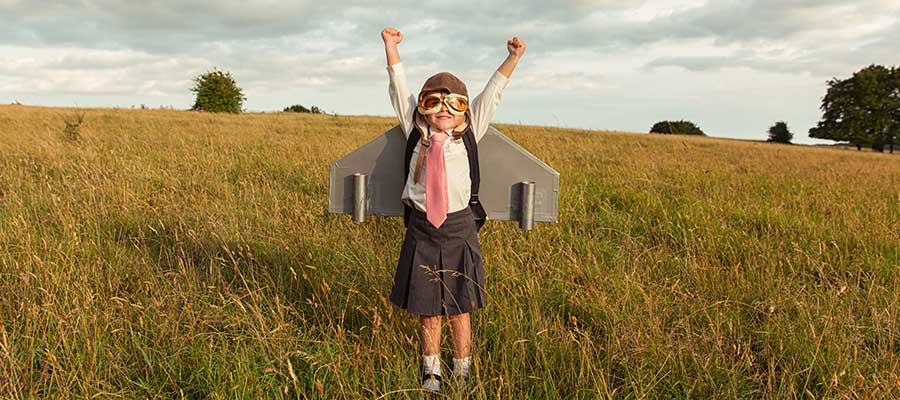 young girl with paper wings and googles getting ready to fly